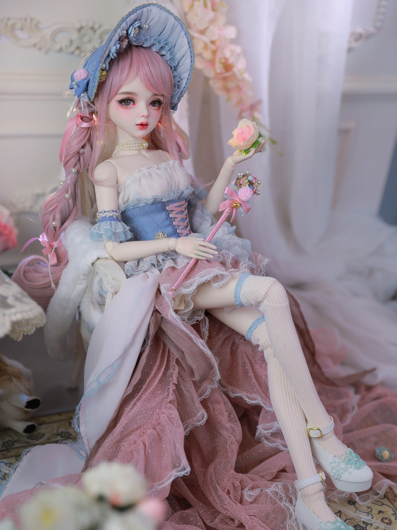 Carla Doll by Sukuroi sitting in a pink and blue dress, with stockings and a floral accessory