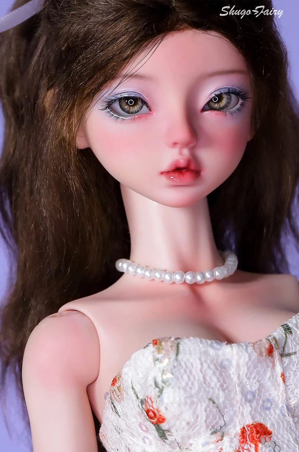 Close-up of a doll in a white Doll Floral Dress with orange flowers and pearl necklace