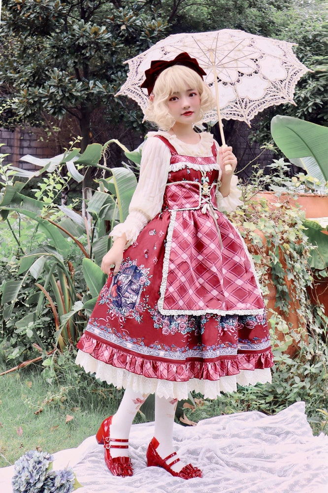 Model in Little Red Riding Hood jumper skirt holding lace umbrella in garden setting