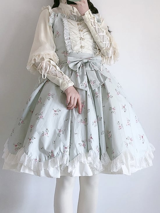 Model in a floral light green jumper skirt with lace trim and bow accents