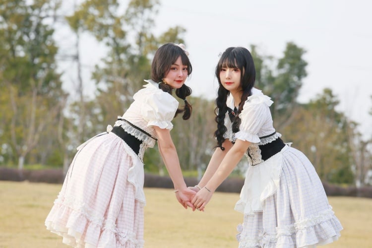 Twins in gingham dresses outdoors